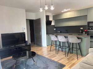 a living room with a kitchen with bar stools at Vibes-city apartman in Nyíregyháza