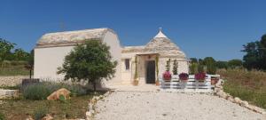 une petite maison blanche avec des fleurs dans un champ dans l'établissement A casa di Claudia, à Martina Franca