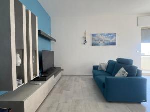 a living room with a blue couch and a tv at Ella Apartment in Otranto