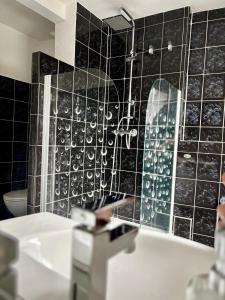 a bathroom with a black tiled wall and a tub at Ferienidyll an der Recknitz in Tessin
