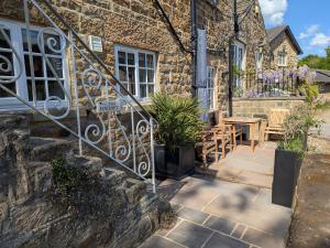 een stenen huis met een patio met een tafel en stoelen bij Bridge House Cottage in Harrogate