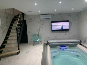 a hot tub in a room with a tv and stairs at Grange&Lodge in Chavelot
