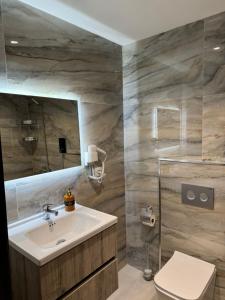 a bathroom with a sink and a toilet and a mirror at Arber Premium Apartment in Durrës