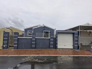 a blue house with a gate and a garage at Kay's Guest House in Kraaifontein