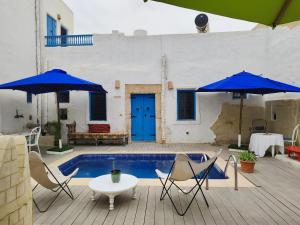 a patio with two blue umbrellas and a pool at Dar Michèle Djerba in Houmt Souk
