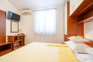 a bedroom with a bed and a desk and a window at Villa Alesa Steva in Tučepi