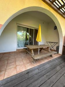 un patio esterno con tavolo da picnic e ombrellone di Résidence KALLISTE a Monticello Altre 5 foto