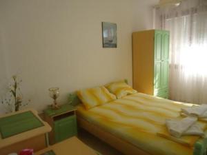 a bedroom with a yellow bed and a window at Тихия кът in Sozopol