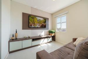 a living room with a couch and a tv on the wall at Achei Itapema • Beira-mar e piscina em Porto Belo in Porto Belo
