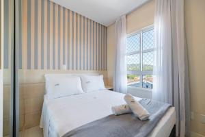 a bedroom with a white bed and a window at Achei Itapema • Beira-mar e piscina em Porto Belo in Porto Belo +45 photos