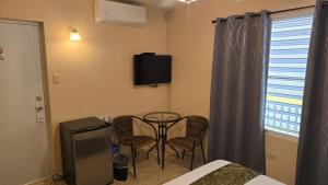 a room with a table and chairs and a tv at I Love Combate Rooms & Suites in Boqueron