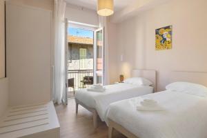 two beds in a white room with a window at Maison Petrolini - Maggiore Estate by Ginin in Cannobio
