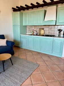 a kitchen with blue cabinets and a blue couch at Appartamento Mare e Natura in Castelsardo