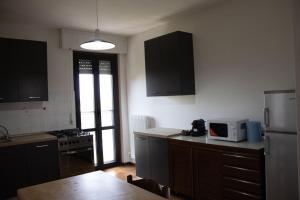 a kitchen with black cabinets and a white refrigerator at B&B San Savino in Piacenza