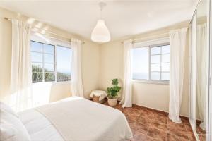 a bedroom with a white bed and windows at Casa Conrado, 2 bedroom modern oasis, good location in Puntallana