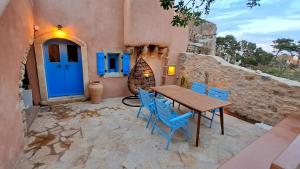 a table and chairs on a patio with a blue door at Rodamia Traditional Cottage in Kythira