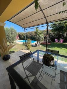 a patio with a glass table and chairs and a pool at Maison de vacances in Le Thor
