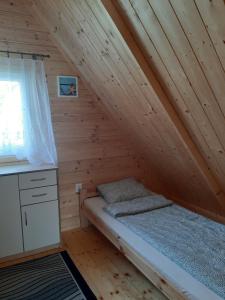 a bedroom with a bed in a wooden attic at Domki Nadmorska Oaza in Sarbinowo