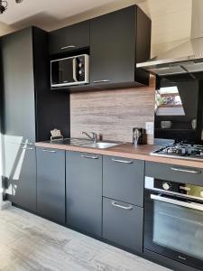 una cucina con lavello e microonde di L'église a Sainte-Marie-au-Bosc Altre 5 foto