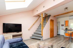 a living room with a couch and a tv and stairs at Kotedzas in Nida