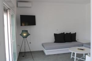 a room with a couch and a table and a tv at Lefkes Beach Suite in Kithnos