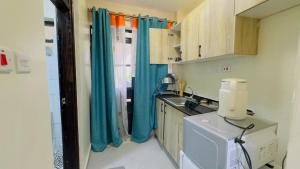 a small kitchen with blue curtains and a sink at Studio apartment Westlands Kitisuru in Nairobi