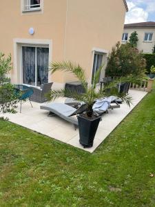 a patio with chairs and a plant in a yard at Villa le jasmin très calme in Andrézieux-Bouthéon