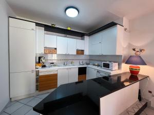 a kitchen with white cabinets and a black counter top at Domus Ortensia in Boscoreale