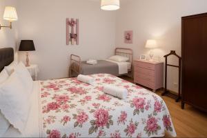 a bedroom with a large bed with a floral blanket at Casa da Praia do Ribatejo - Casa da Arcada in Praia do Ribatejo