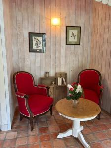 a room with two chairs and a table with a vase of flowers at La Reboursière in Notre-Dame-du-Pé
