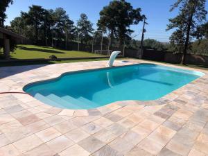 a swimming pool in a yard with a tile patio at Chácara Alta Vista em Londrina in Londrina