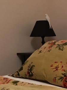 a bird perched on top of a bed with a lamp at A Vol D'Oiseau in Honfleur