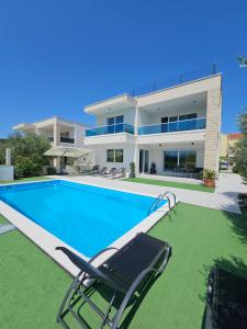 a house with a swimming pool with a chair and a house at Villa Maestro in Sreser