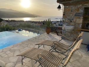 a patio with two wooden chairs and a pool at Aegean Panorama Hideaway & Pool in Samos in Vathý