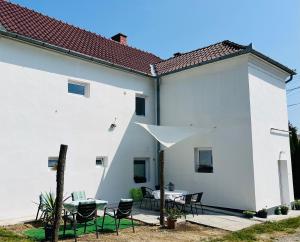 a white building with a patio with a table and chairs at Téesz Vendégház in Zalaháshágy