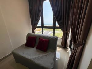 a chair with two red pillows sitting in front of a window at Luxury & Lovely studio with waterpark in town in Melaka +8 photos