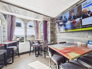 a restaurant with tables and chairs and a tv on the wall at Kings Boutique Hotel in Blackpool
