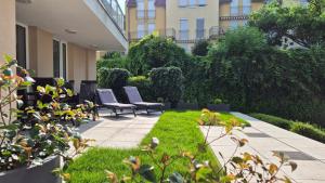 a garden with chairs and grass and a building at Spa Residence Carbona 101, 307 Apartman in Hévíz
