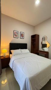 a bedroom with a large white bed and a guitar at Villa Ostara Kota Batu in Batu