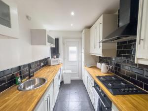 a kitchen with white cabinets and a sink at Clydebank 2 Bedroom Home in Drumchapel