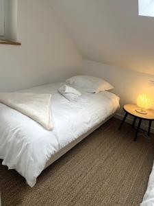 a bed with white sheets and pillows and a table at Sejour de charme au bohème in Amboise +10 photos