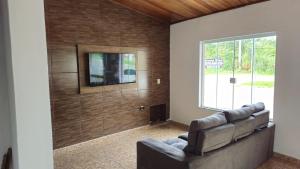 a living room with a couch and a tv on a wall at Pousada Passos de Fé in Aparecida
