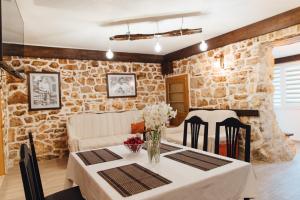 een eetkamer met een tafel en een stenen muur bij Kamena Oaza in Stolac