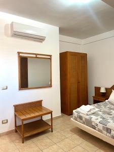 a bedroom with a bed and a mirror and a table at Riviera Village Family Hotel in Butera
