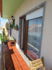 Un balcón con un banco y una gran ventanal. en Casa Belos Ares, en Ferrel