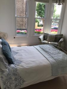 una camera da letto con un letto con due sedie e due finestre di Banks Road a West Kirby