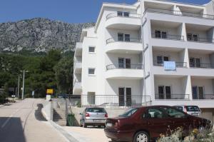 un edificio bianco con macchine parcheggiate di fronte di Apartments Bota a Drvenik