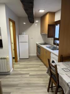 a kitchen with a white refrigerator and wooden cabinets at Casa San Antonio in Albarracín
