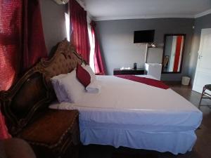 a bedroom with a bed with white sheets and red curtains at Kimberland Guest House Block 10 in Gaborone +55 photos