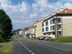 une rue avec des bâtiments et des voitures garés sur le côté de la route dans l'établissement Apartamento a estrenar Mar de Cunchas, à San Martín de Arriba